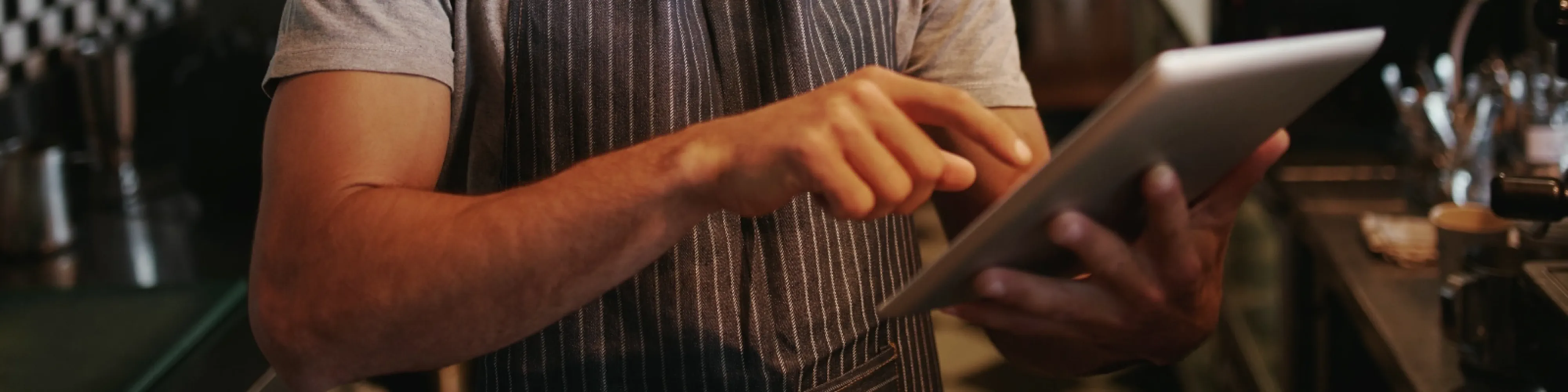 Ondernemer bekijkt telefoon in zijn keuken